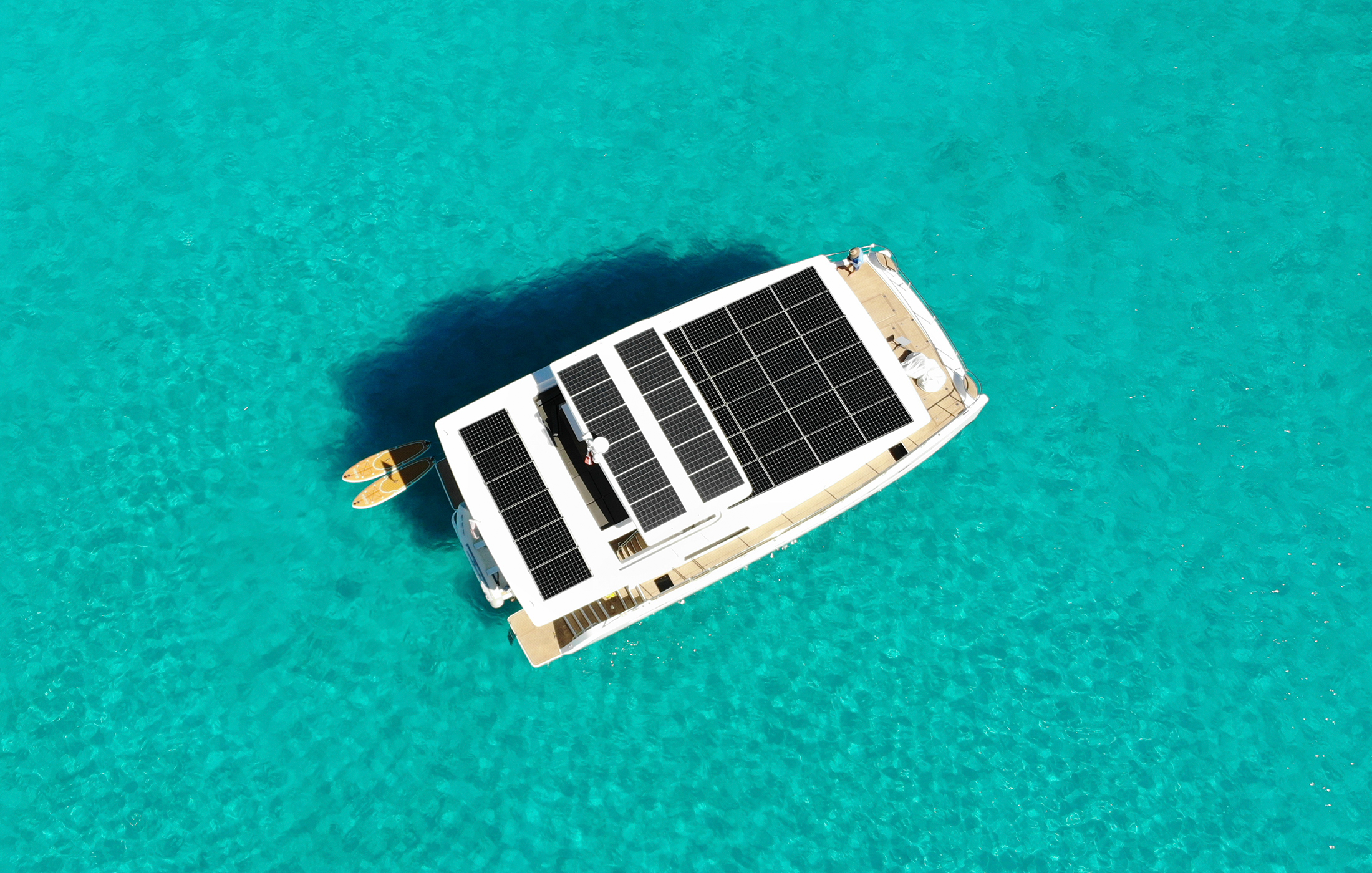 electric yacht with solar panels on the roof anchored in crystal clear waters